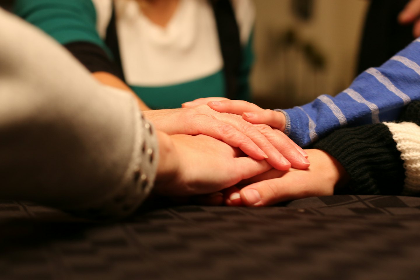 Four hands of different ages stacked together showing unity.