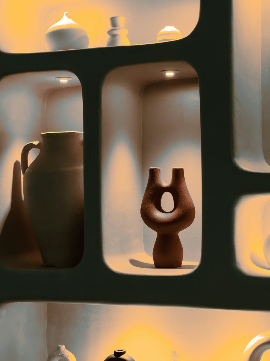 Handcrafted ceramic vases and abstract sculptures displayed on a shelf.