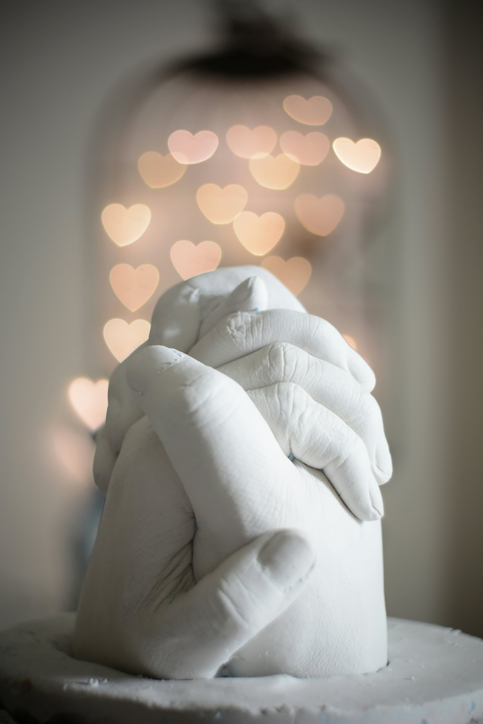 A plaster cast of an adult hand holds a child's hand.